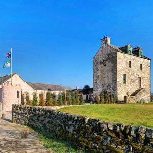 un antiguo edificio de piedra detrás de una pared de piedra en Buittle Castle Exclusive Use- Stay in your own Castle! en Castle Douglas