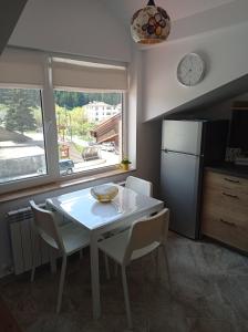 a kitchen with a white table and chairs and a clock at Къща за гости-Ганеви in Zmeitsa +16 photos