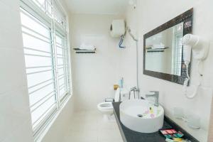 a white bathroom with a sink and a toilet at Nhà nghỉ Đức Trọng in Móng Cái