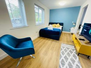 a bedroom with a blue bed and a blue chair at KENILWORTH STUDIO * GROUND FLOOR * PARKING in Kenilworth