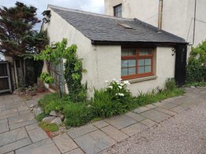 Braeview Studio في Macduff: بيت ابيض مع شباك وبعض النباتات