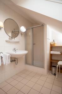 een badkamer met een douche, een wastafel en een spiegel bij Gästehaus Heintz in Merzig