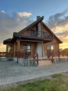 a log home with a sunset in the background at Skrajna Chata Chrzypsko in Chrzypsko Wielkie