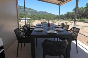 a black table with chairs and a table with wine glasses at Robinson olive tree huts in Čara