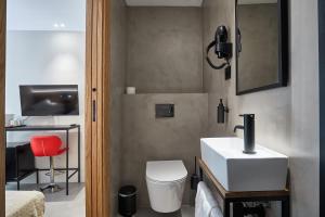 ein Badezimmer mit einem weißen Waschbecken und einem roten Stuhl in der Unterkunft Ella Hostel Ramblas in Barcelona