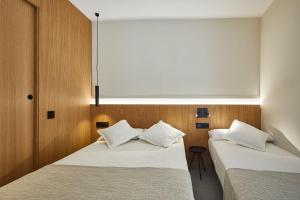 two beds in a room with wooden walls at Ella Hostel Ramblas in Barcelona