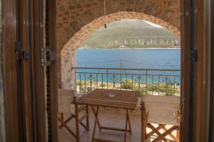 a table and chairs on a balcony with a view of the water at Mani Blue Studios in Oitylo