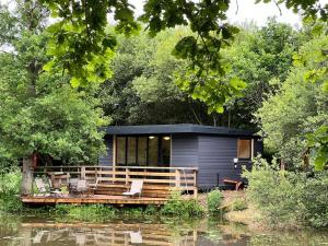 a tiny house on a dock on a river at Cackle hill lakes, Kingfisher Lodge in Biddenden