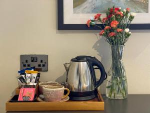 The Atlantic في Hugh Town: طاولة مع وعاء القهوة و مزهرية مع الزهور