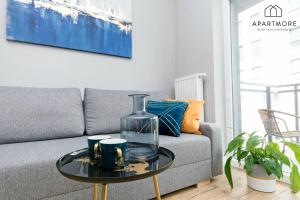 a living room with a couch and a glass vase on a table at City Center - Wałowa by Apartmore in Gdańsk