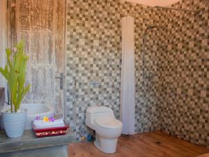 łazienka z toaletą i wanną z rośliną w obiekcie The Winaposa w mieście Munduk