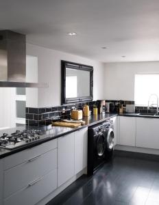 a kitchen with a stove and a washer and dryer at Gorgeous 3 Bedroom Victorian Townhouse in Lisburn