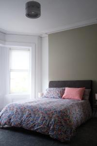 a bedroom with a bed with a colorful comforter and a window at Gorgeous 3 Bedroom Victorian Townhouse in Lisburn