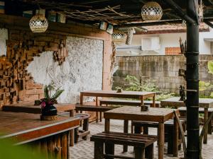 a restaurant with wooden tables and benches and a wall at The Winaposa in Munduk