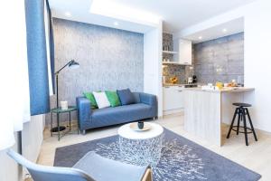 a living room with a blue couch and a kitchen at Vagabond Corvin in Budapest