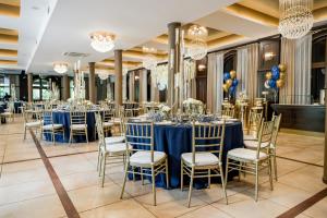 un salón de banquetes con mesas y sillas azules y lámparas de araña en Hotel RED en Ostrowiec Świętokrzyski