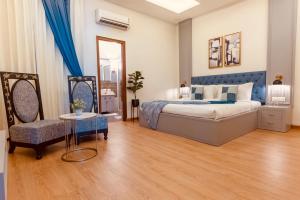 a bedroom with a large bed and a chair at Silver Leaf Apartments in Amritsar
