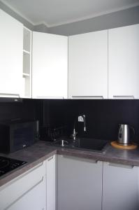 a kitchen with white cabinets and a sink at Apartament Cesarski in Wałcz