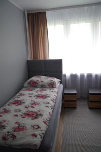 a bedroom with a bed with a floral comforter at Apartament Cesarski in Wałcz