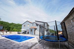 een huis met een zwembad naast een gebouw bij Villa with a heated private pool, parking, BBQ in Petričevići