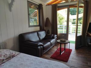 a living room with a leather couch and a table at Chambre d hôte dans un magnifique chalet in Pontenx-les-Forges