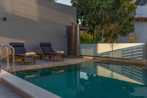 una piscina con due sedie e una fontana di Paligremnos Residences, a Beachside Retreat, By ThinkVilla a Plakiás