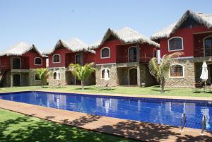 a row of red houses with a swimming pool at Flat La Fazenda in Canoa Quebrada