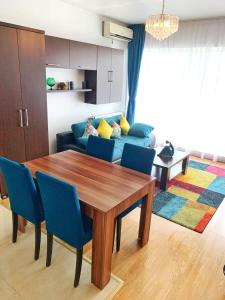 a living room with a wooden table and blue chairs at Long Term Business Apartment in Cluj-Napoca