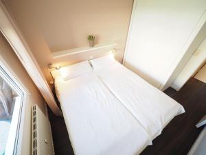 Ce lit se trouve dans une petite chambre dotée d'une fenêtre. dans l'établissement Appartement-173, à Westerland
