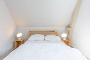 ein weißes Bett mit zwei weißen Kissen und zwei Lampen in der Unterkunft Bootshaus in Husum