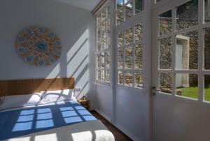 1 dormitorio con 1 cama, ventanas y puerta en Apartamentos Bestarruza en Mugardos