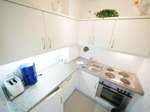 eine kleine Küche mit weißen Schränken und einem Waschbecken in der Unterkunft Appartement 162 in Westerland