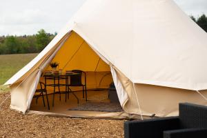 a yellow and white tent with a table inside at Forest Edge Glamping in Gittisham