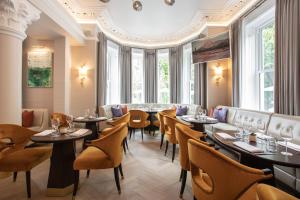 a restaurant with tables and chairs and windows at Tullyglass House Hotel in Ballymena