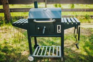 a black grill sitting in the grass next to a bench at Mirror house in Tīnūži