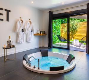 uma casa de banho com banheira no meio de um quarto em Le Secret - Nuit romantique avec Jacuzzi privatif - Champagne offert - Climatisation em Nantes