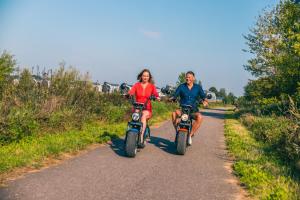 Mężczyzna i kobieta jeżdżący motocyklami po drodze w obiekcie EuroParcs De Kraaijenbergse Plassen w mieście Groot-Linden