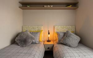 The Beach Hut, Burghead في Burghead: غرفة نوم بسريرين ومصباح على طاولة