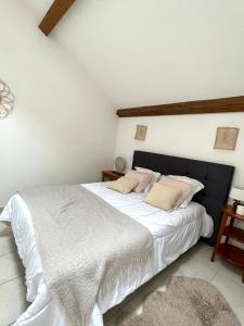 een slaapkamer met een groot bed met witte lakens en roze kussens bij "Les Oiseaux" avec terrasse, parking, duplex in Le Chambon-sur-Lignon