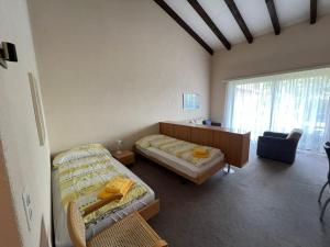 a bedroom with two beds and a desk and a window at Ascona: Sabrina Apt. 237 in Ascona