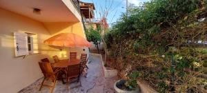 eine Terrasse mit einem Tisch mit Stühlen und einem Sonnenschirm in der Unterkunft The Athenian Riviera Summer Nest in Anavyssos