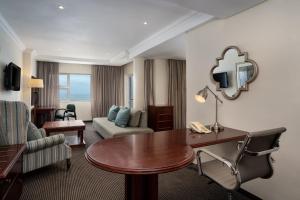 um quarto de hotel com uma mesa e um sofá em Premier Hotel Regent em East London