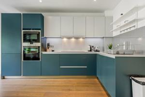 a kitchen with blue cabinets and white appliances at Three Bedroom Serviced apartment in Old Street in London