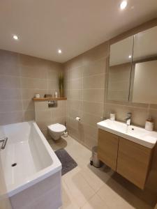 a bathroom with a tub and a toilet and a sink at Appartement Gentiane de 85m2 avec sauna à 10 min des pistes in Sainte-Foy-Tarentaise