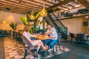 a man and woman sitting at a table in a restaurant at EuroParcs De Kraaijenbergse Plassen in Groot-Linden