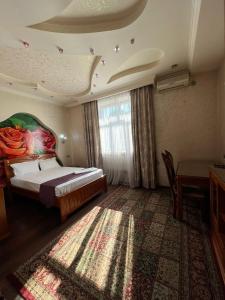 a bedroom with a bed and a table and a window at Akzhol Hotel Almaty in Almaty