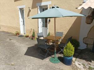 une table et des chaises sous un parapluie bleu dans l'établissement Colourful well equipped 2-Bed House in Le Vigeant, à Le Vigeant