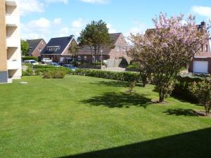 einen Hof mit grünem Gras, Bäumen und Häusern in der Unterkunft Appartement 84 in Westerland