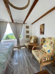 a bedroom with a bed and chairs and a window at Casutele verzi din Ocnele Mari in Ocnele Mari
