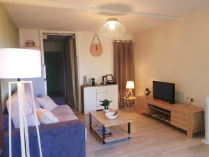 a living room with a couch and a tv at Détente au Cœur de la Station in Métabief